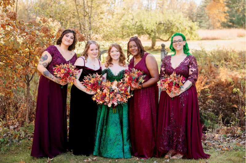 Bride and bridesmaids holding faux rust, burgundy and orange wedding bouquets outdoors