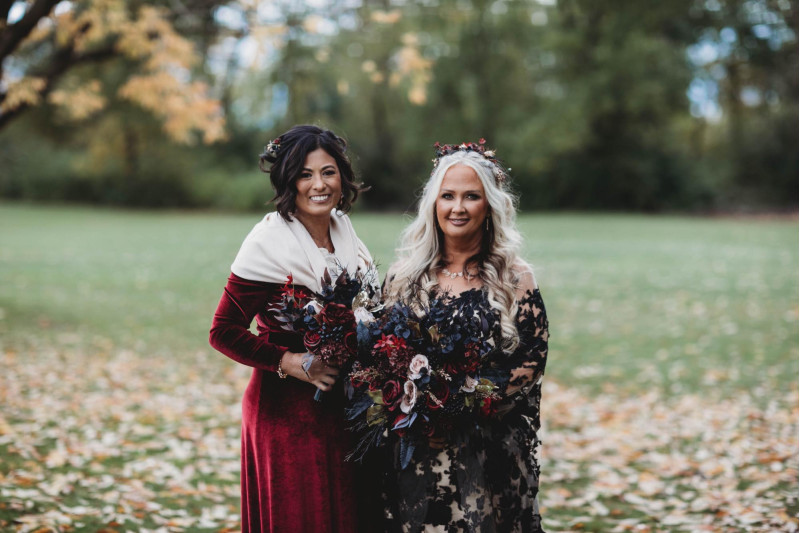 Boho-glam bouquet with burgundy florals, black leaves, beige petals, and gold touches