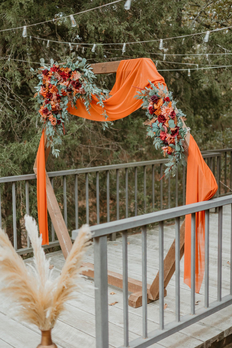 Boho floral arch in warm burgundy, dusty rose, and terracotta tones with silk blooms