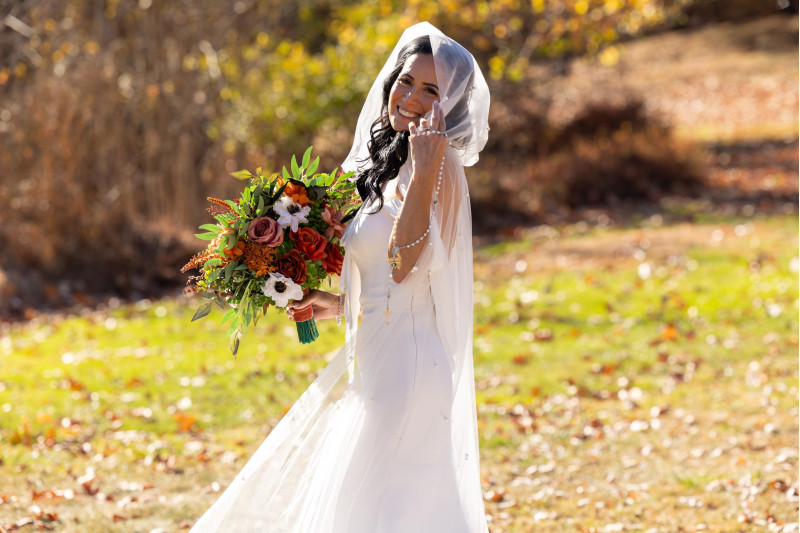 bride outdoors holding terracotta, cinnamon, rust and ivory bridal bouquet