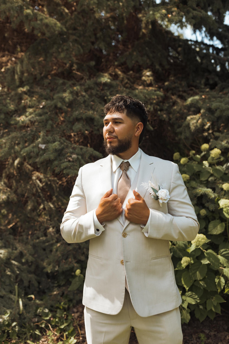 Groom portrait in light suit with ivory boutonniere and neutral wedding flowers