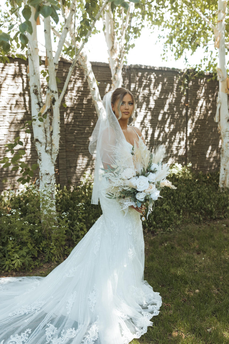 Bride portrait in lace gown with ivory pampas wedding bouquet in natural garden