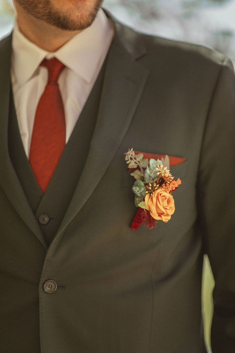 Artificial wedding boutonniere in rust, burgundy, cinnamon, and orange tones