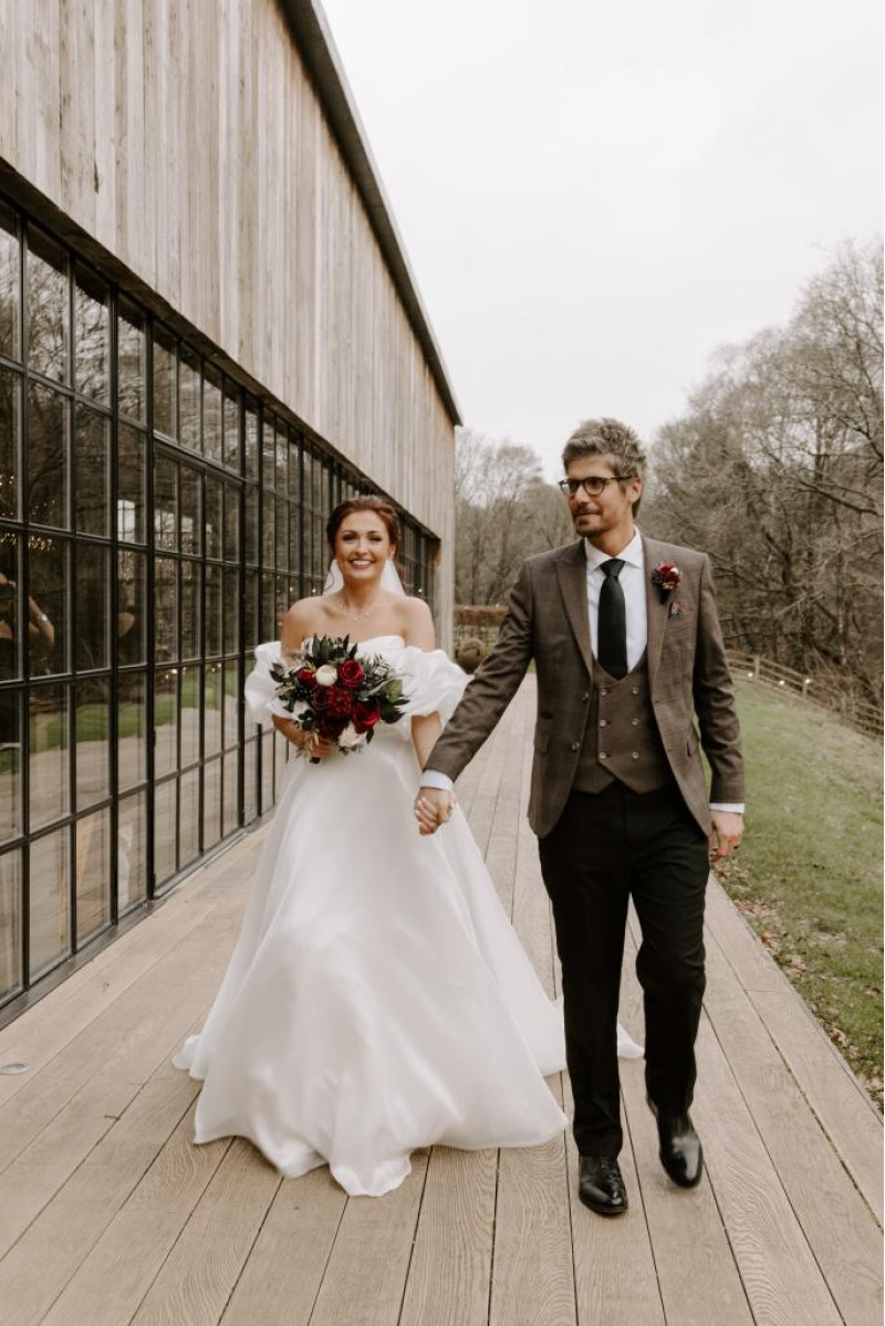 bride and groom walking with black, gold, burgundy and ivory wedding bouquet