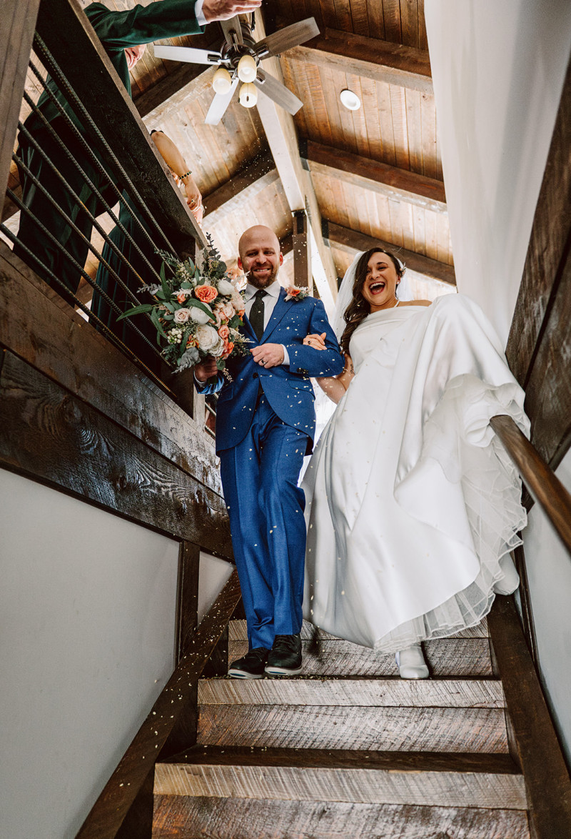 Bride and groom walking down staircase after ceremony with peach and blush pink wedding bouquet1090-1174.3119266055