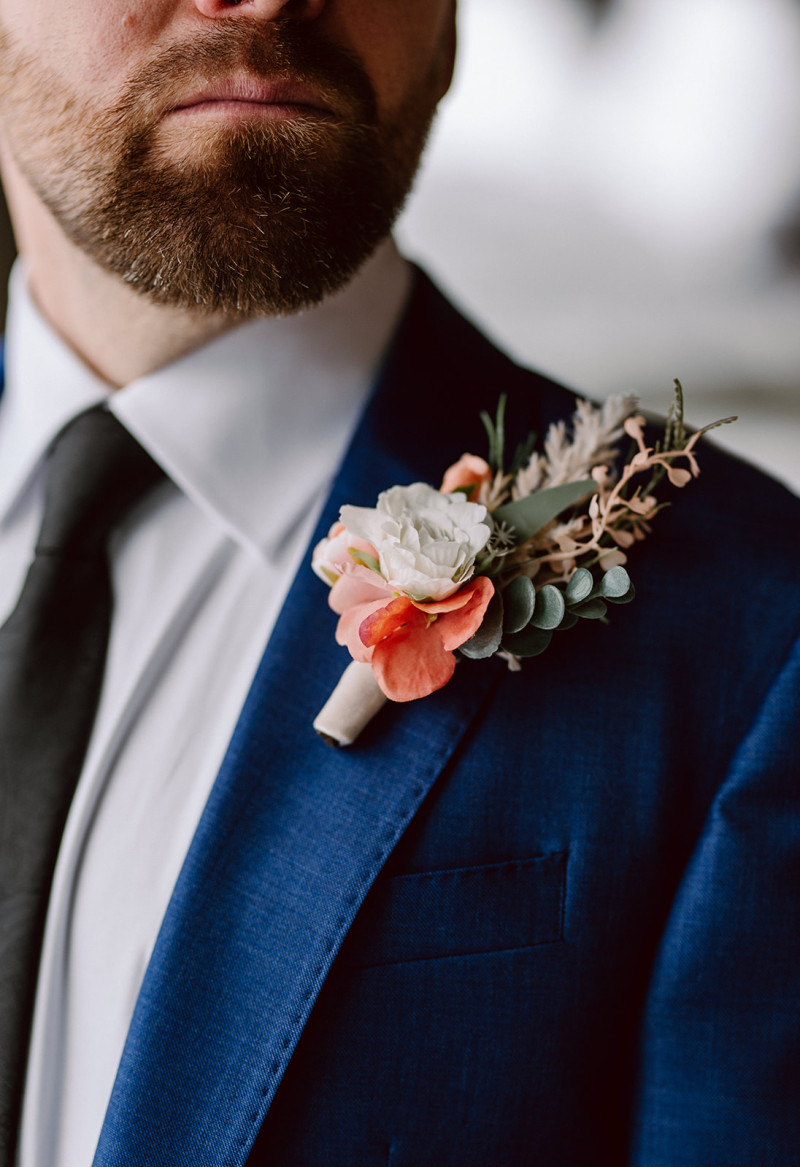 Groom in blue suit with peach and blush pink boutonniere and greenery1096-1167.8832116788