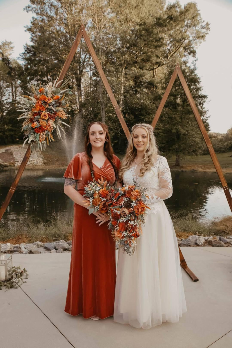 Cascading bridal bouquet and floral arch in rust, terracotta, and burnt orange with silk flowers