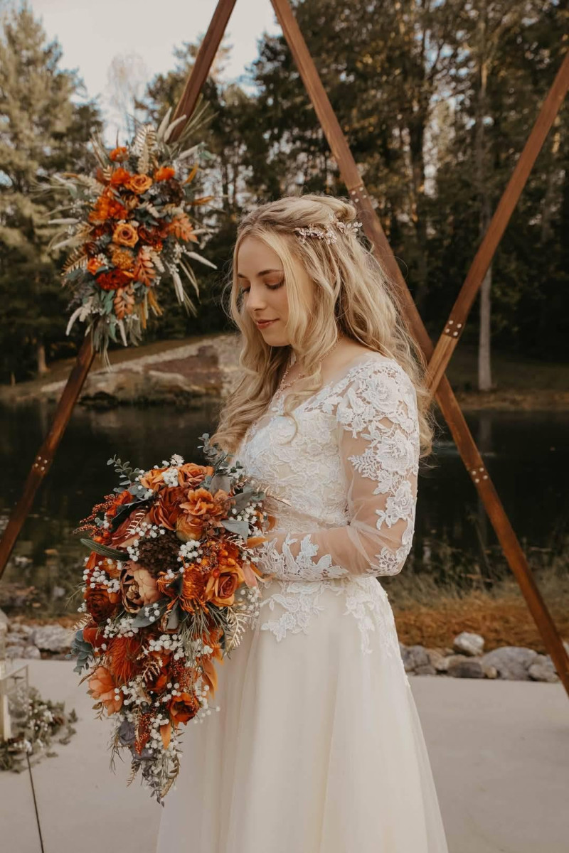 Wedding arch and waterfall bouquet in warm rust, terracotta, and burnt orange tones