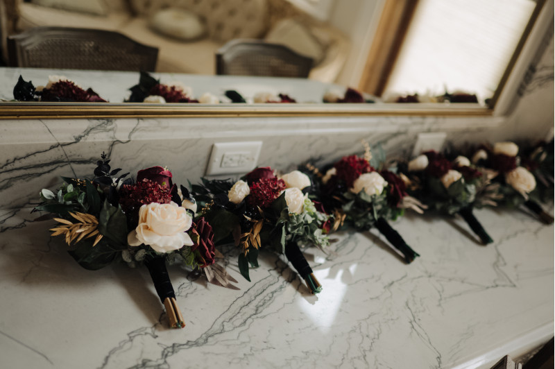 Complete wedding flower collection in burgundy, black, ivory, and gold