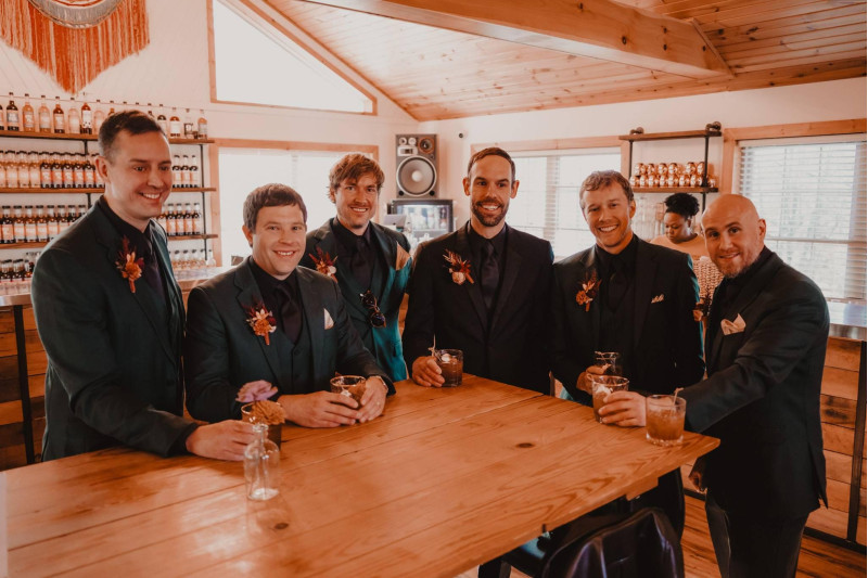 Groom and groomsmen boutonnieres in burgundy and terracotta wedding color palette