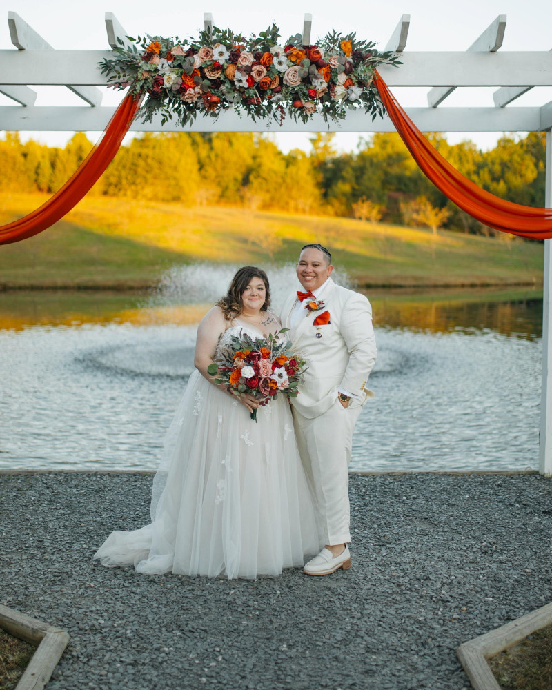 Wedding arch flowers in burgundy, rust, ivory, and cinnamon with coordinated bridal bouquet