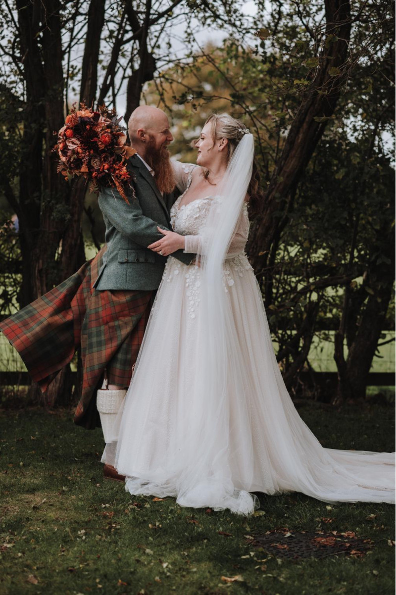 bride and groom with plum, purple, orange, rust and beige wedding bouquet