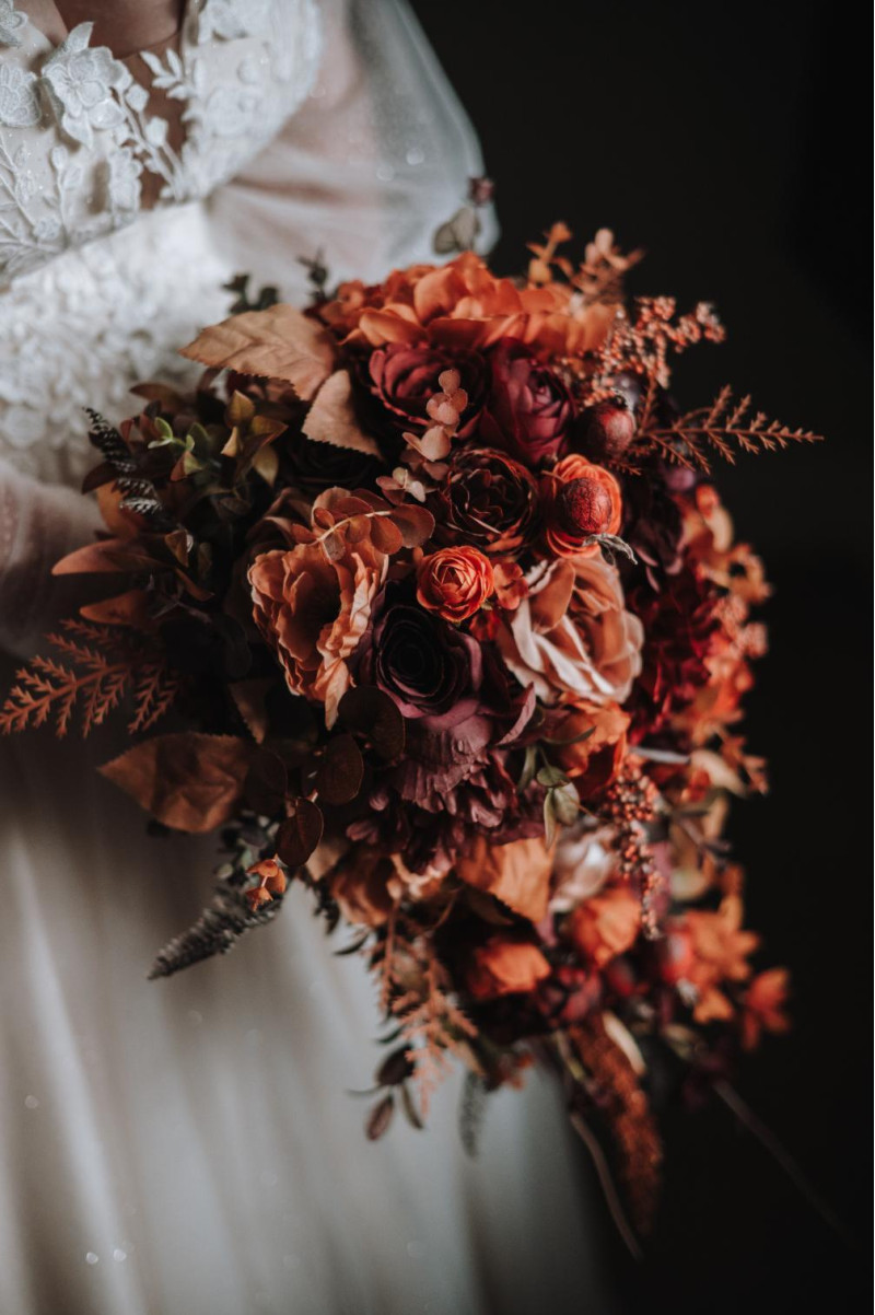 close-up bridal bouquet in plum, purple, orange, rust and beige tones