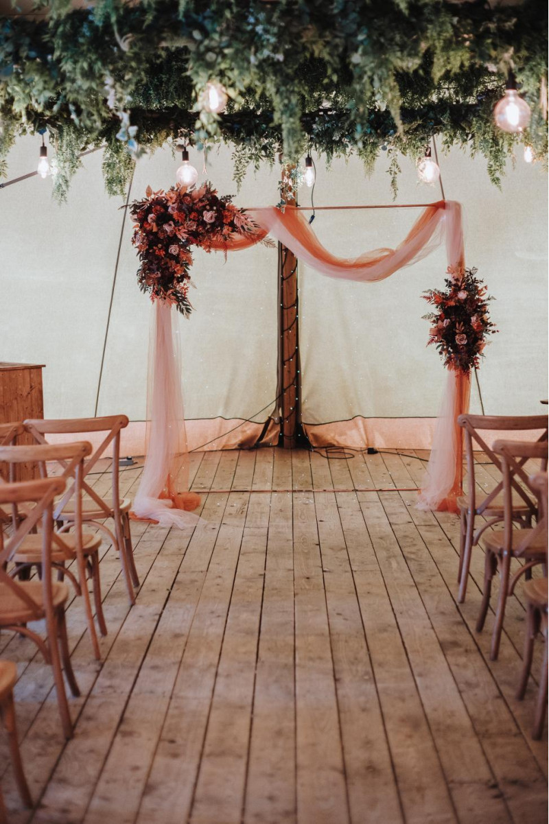 wedding arch with plum, purple, orange, rust and beige floral arrangements and draping972-1201.646090535
