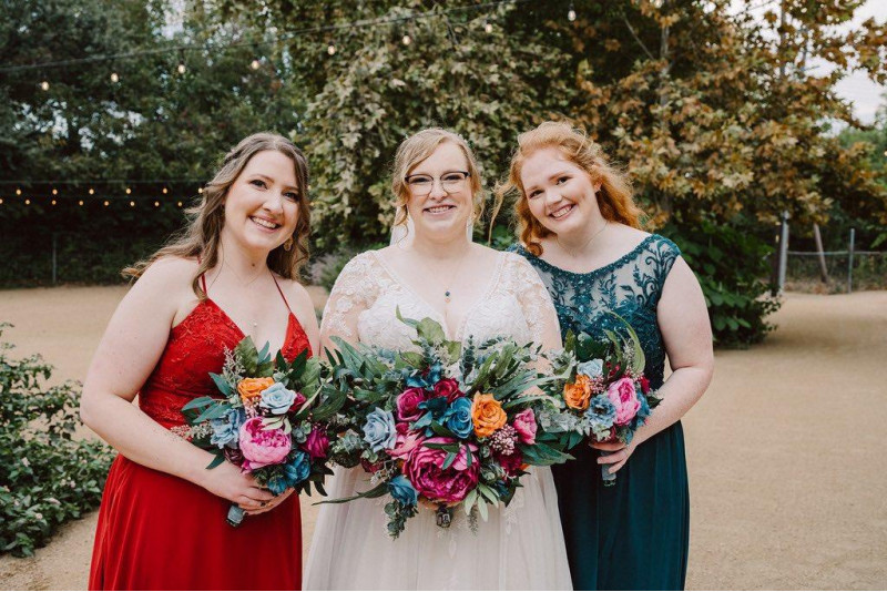 Bold wedding bouquet in emerald, orange, magenta, and teal with vibrant faux blooms