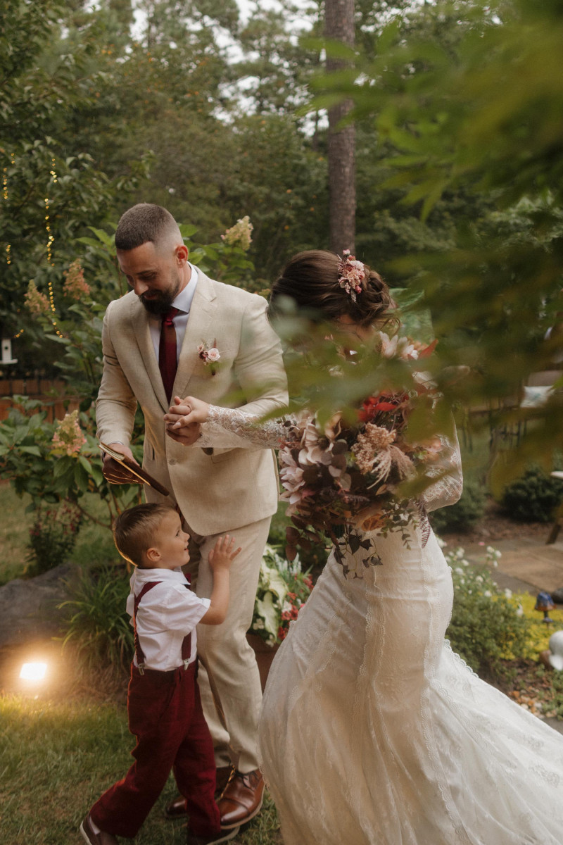 beige mocha and burgundy wedding couple in garden, bride holding bouquet and groom in beige suit
