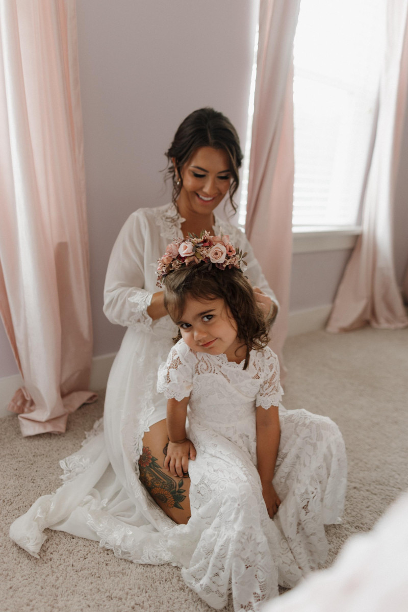 bride styling flower girl with floral crown, beige mocha and burgundy wedding details, bridal hair comb visible