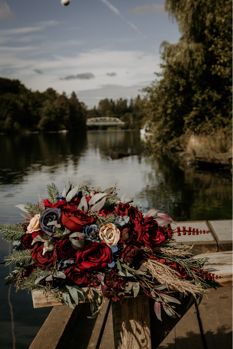 Burgundy navy blue and gold bridal bouquet with red roses blue accents and lush greenery