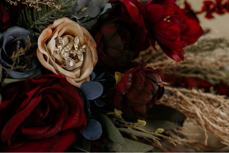 Burgundy navy blue and gold wedding bouquet detail with bridal earrings deep red roses and navy blooms