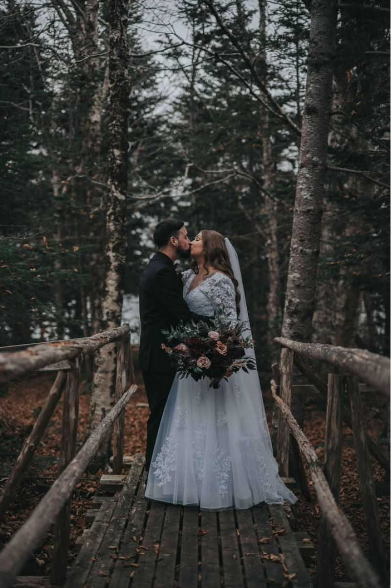 Purple, Burgundy & Beige wedding bouquet, bride and groom kissing on wooden bridge