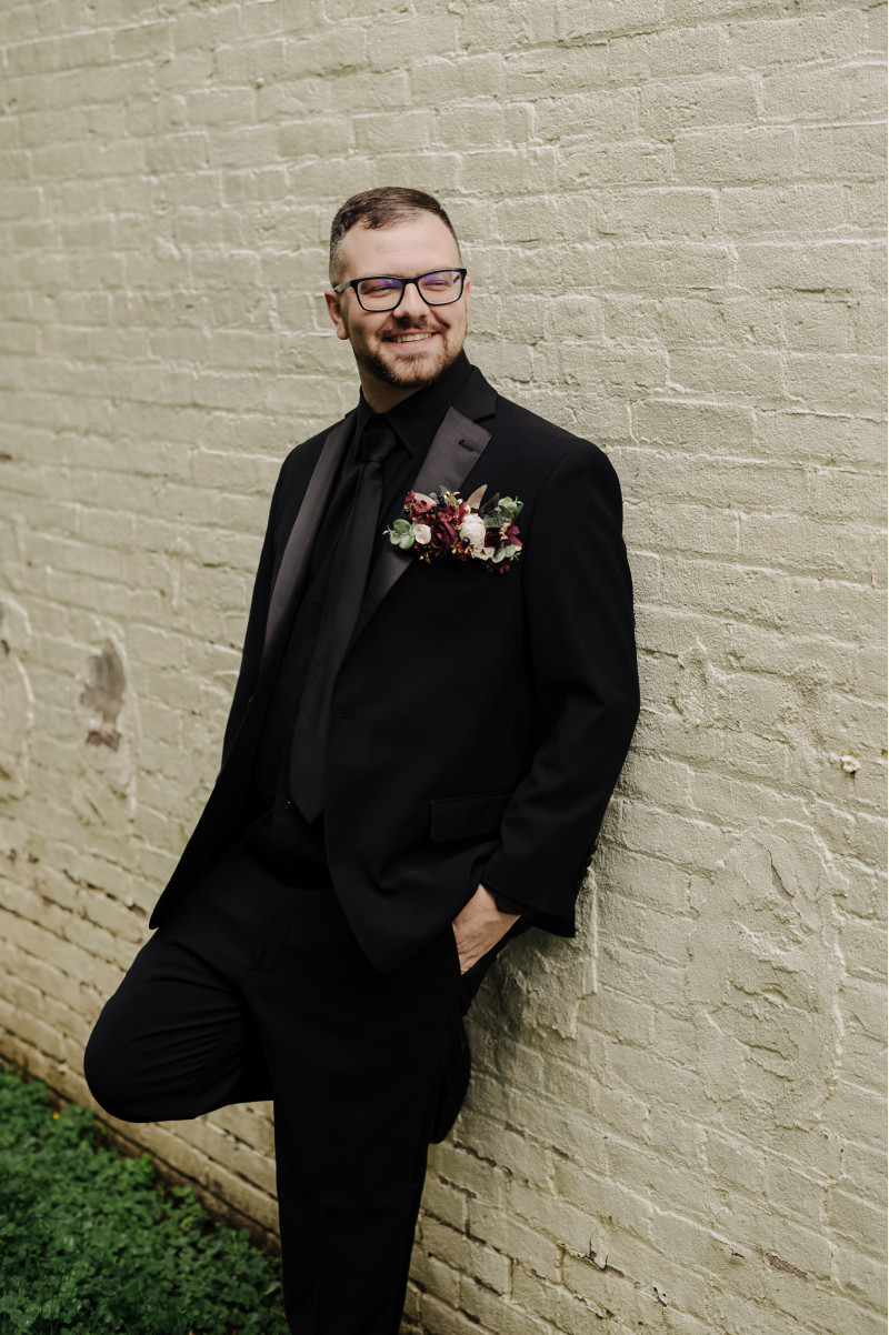 Groom’s boutonniere in burgundy, gold, and black with ivory floral detail