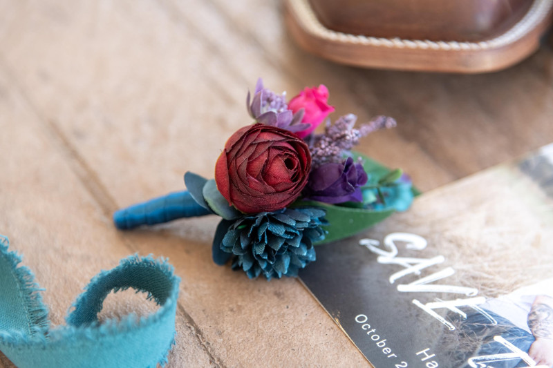 Purple, Teal, Red & Magenta boutonniere, jewel tone wedding details on wooden surface3000-533.86666666667