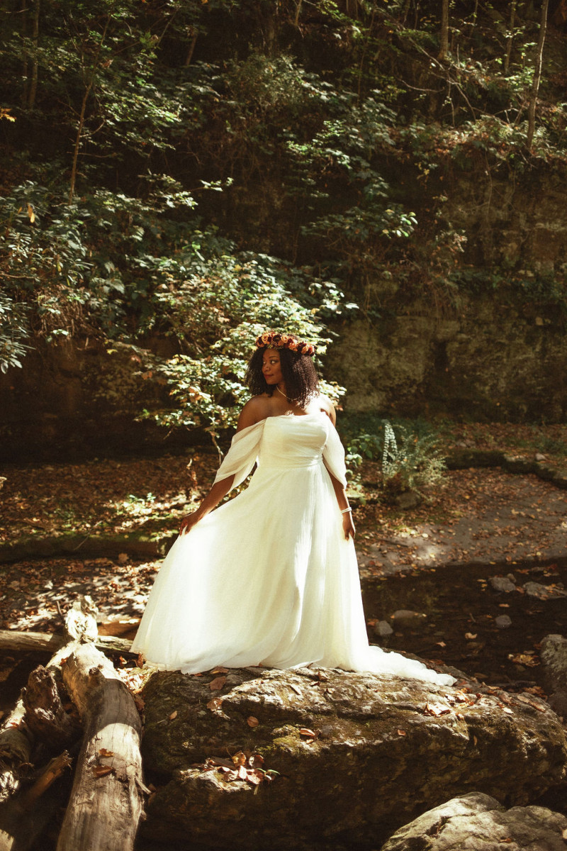 Bride wearing a rust, burgundy, and cinnamon flower crown in a natural forest setting for an intimate autumn wedding