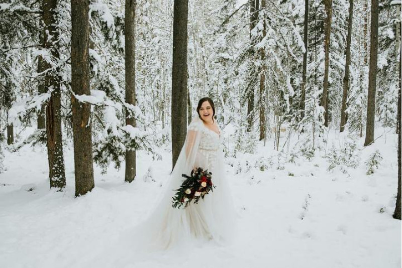 Bride with burgundy gold ivory wedding bouquet in snowy forest