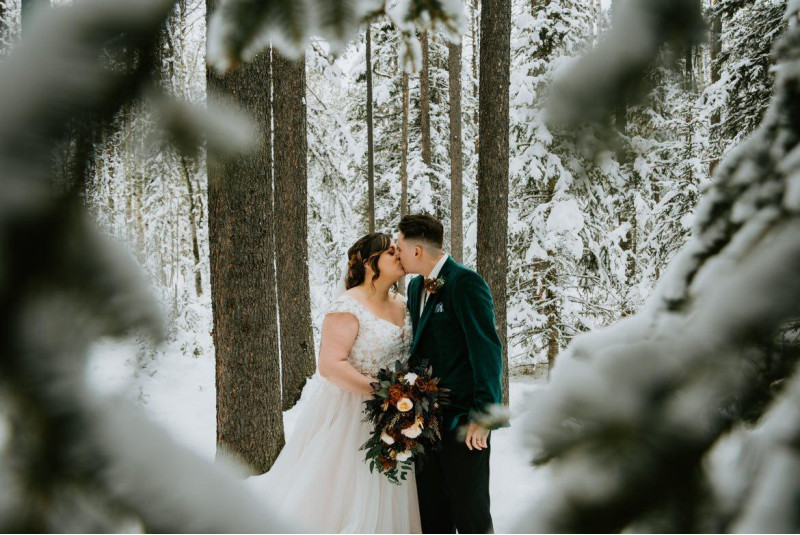 Bride and groom with burgundy ivory bouquet in winter forest