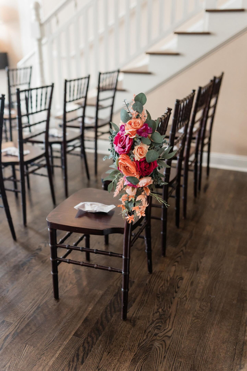 Magenta peach and coral faux floral aisle chair decoration for wedding ceremony