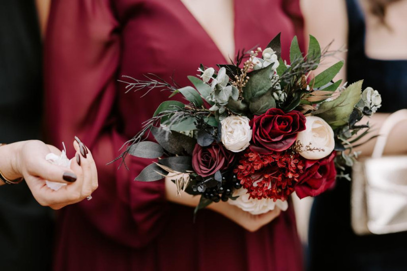 bridesmaid holding black, gold, burgundy and ivory wedding bouquet close-up1024-533.59375