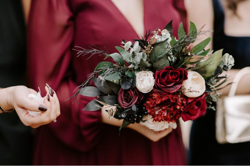 bridesmaid holding black, gold, burgundy and ivory wedding bouquet close-up
