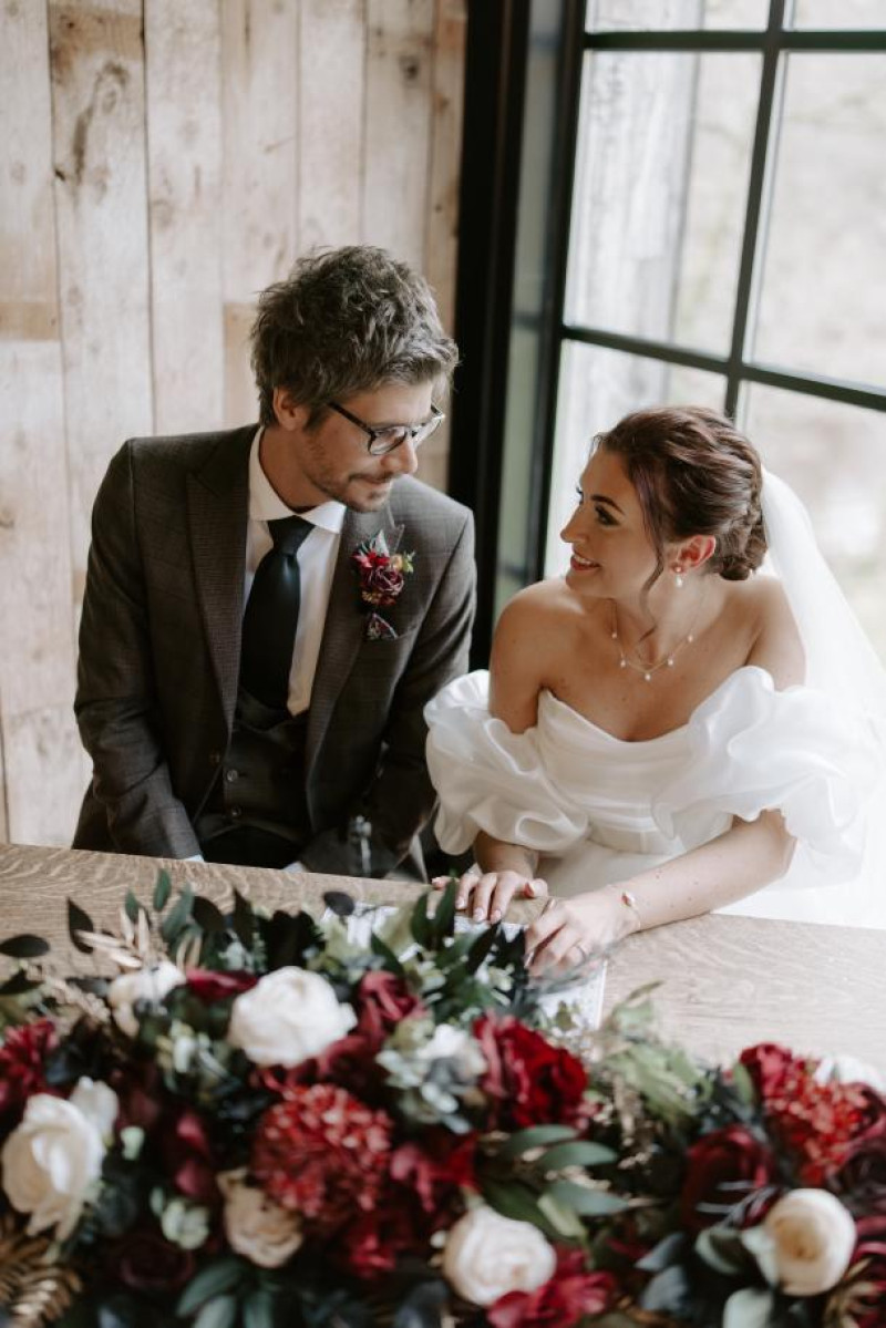 bride and groom seated with black, gold, burgundy and ivory floral centerpiece609-1199.3431855501