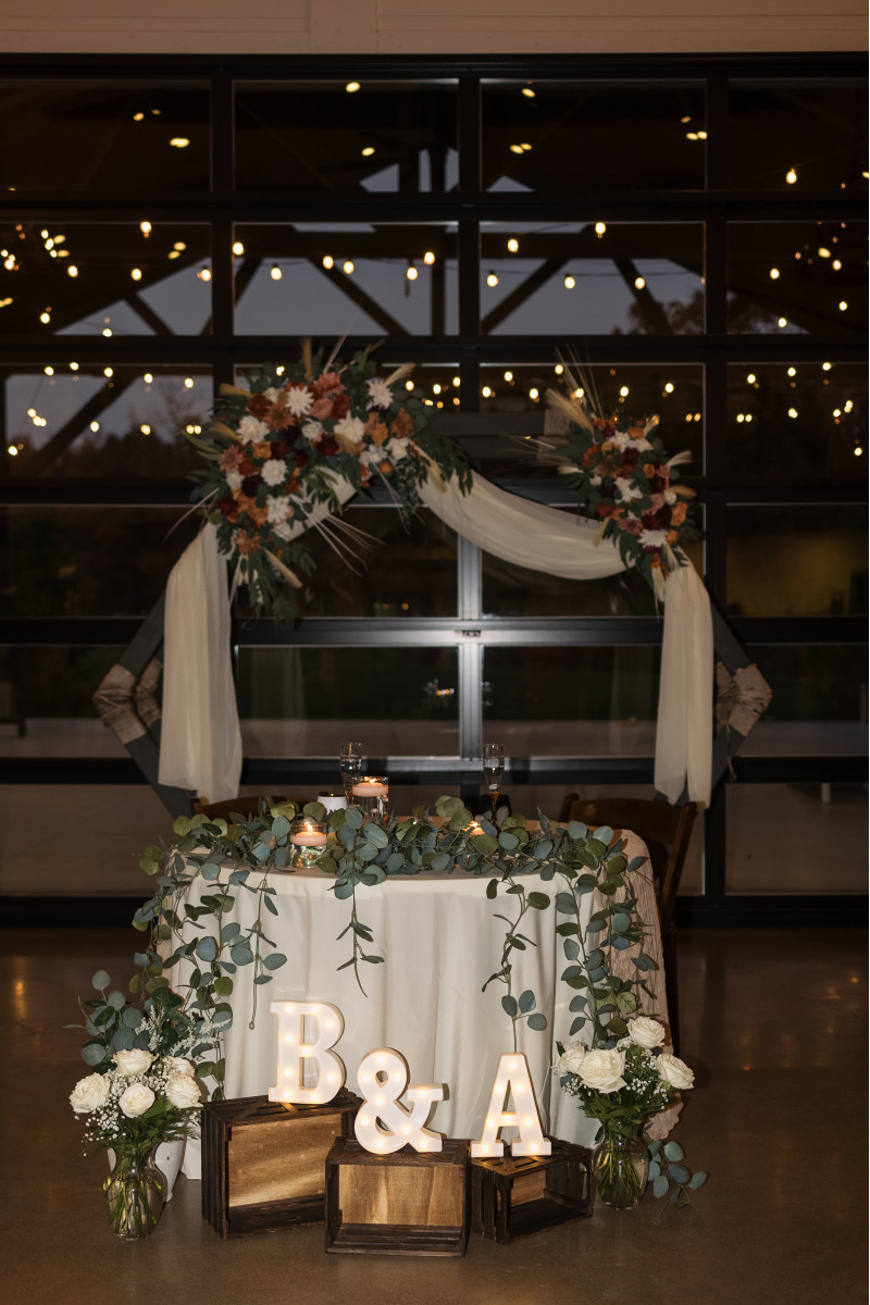 Boho wedding arch flowers with pampas grass, cinnamon roses, ivory dahlias, and burgundy accents