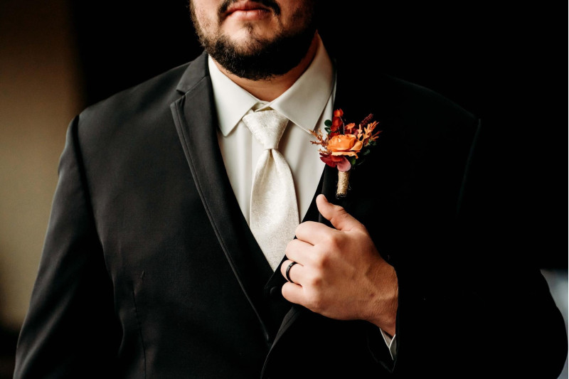 Wedding boutonniere in burgundy, dusty rose, terracotta, and rust with silk flowers